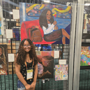 Student smiling and standing in front of their artwork presented at a conference