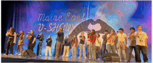 Maine East Students Standing In Front of a V-Show Set