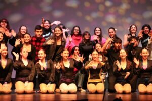 Three rows of Maine West students waving to the camera.